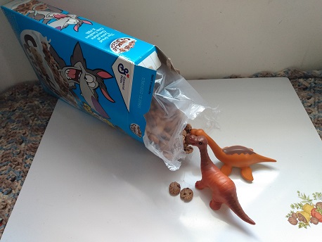 Dinosaurs eating Cookie Crisp cereal right out of the box.
