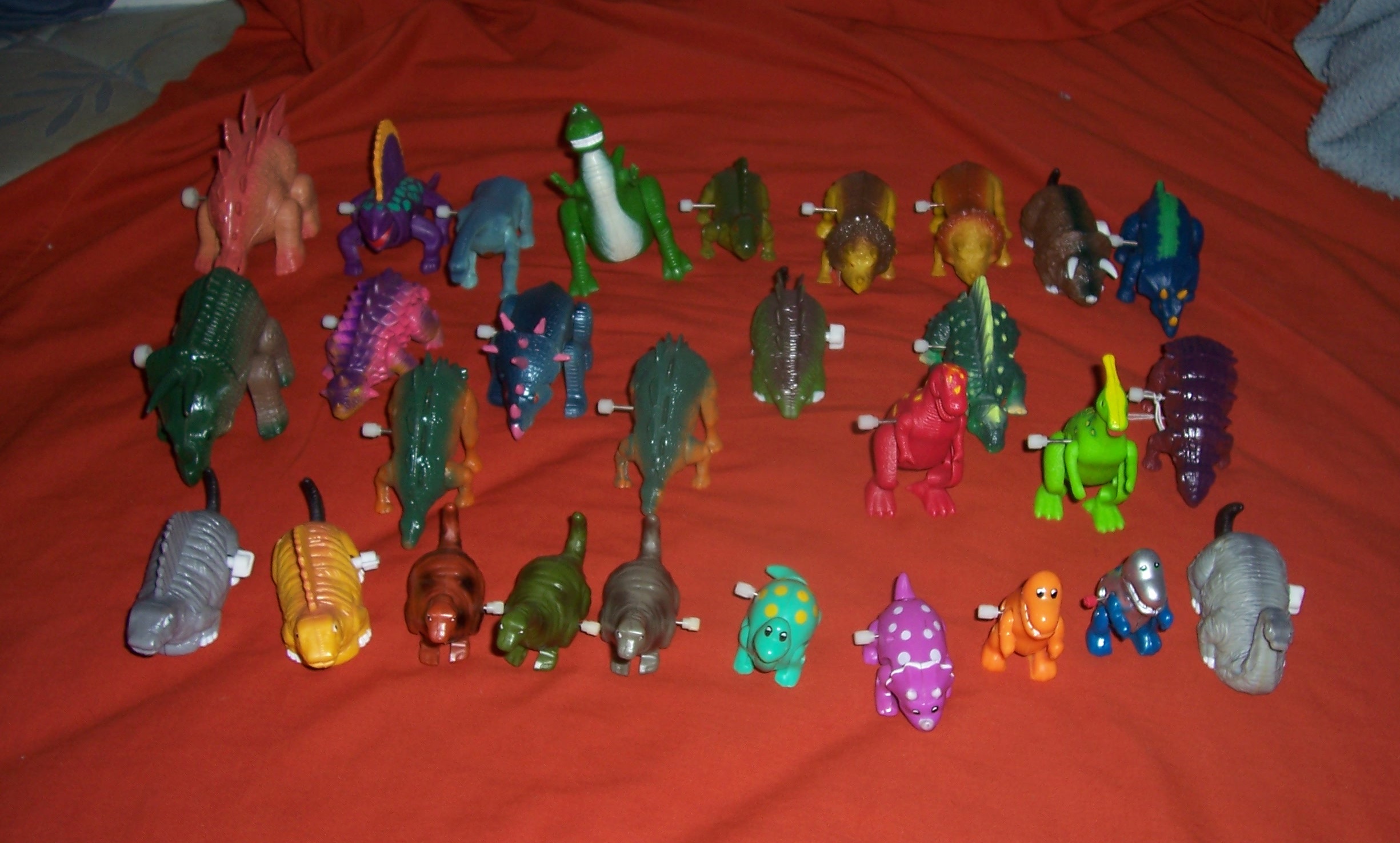 A LOT OF WINDUP DINOSAURS ON BED